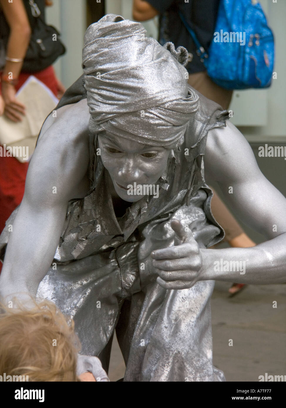 Silver Painted Street performer entertainer entertaining children Covent Garden London WC2 England turban funny hat mime artist Stock Photo