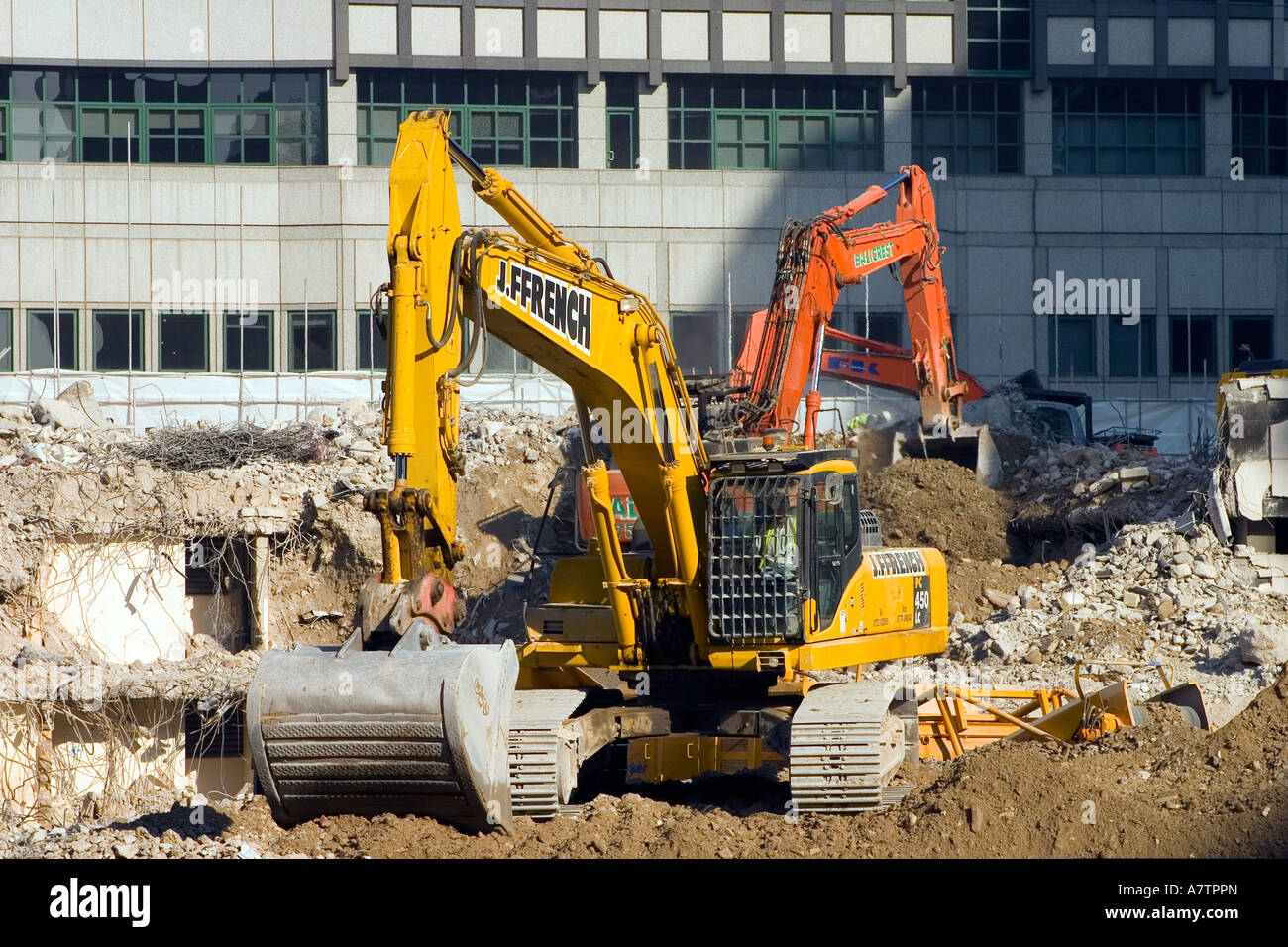 Two JCBs clearing rubble in front of office block Stock Photo