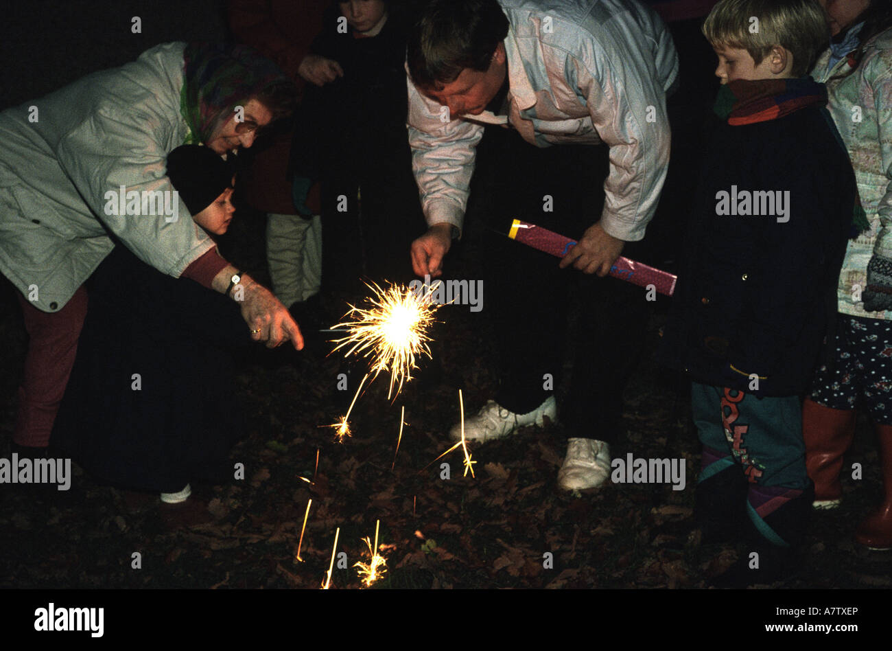 Family celebrating Guy Fawkes night lighting sparklers Stock Photo
