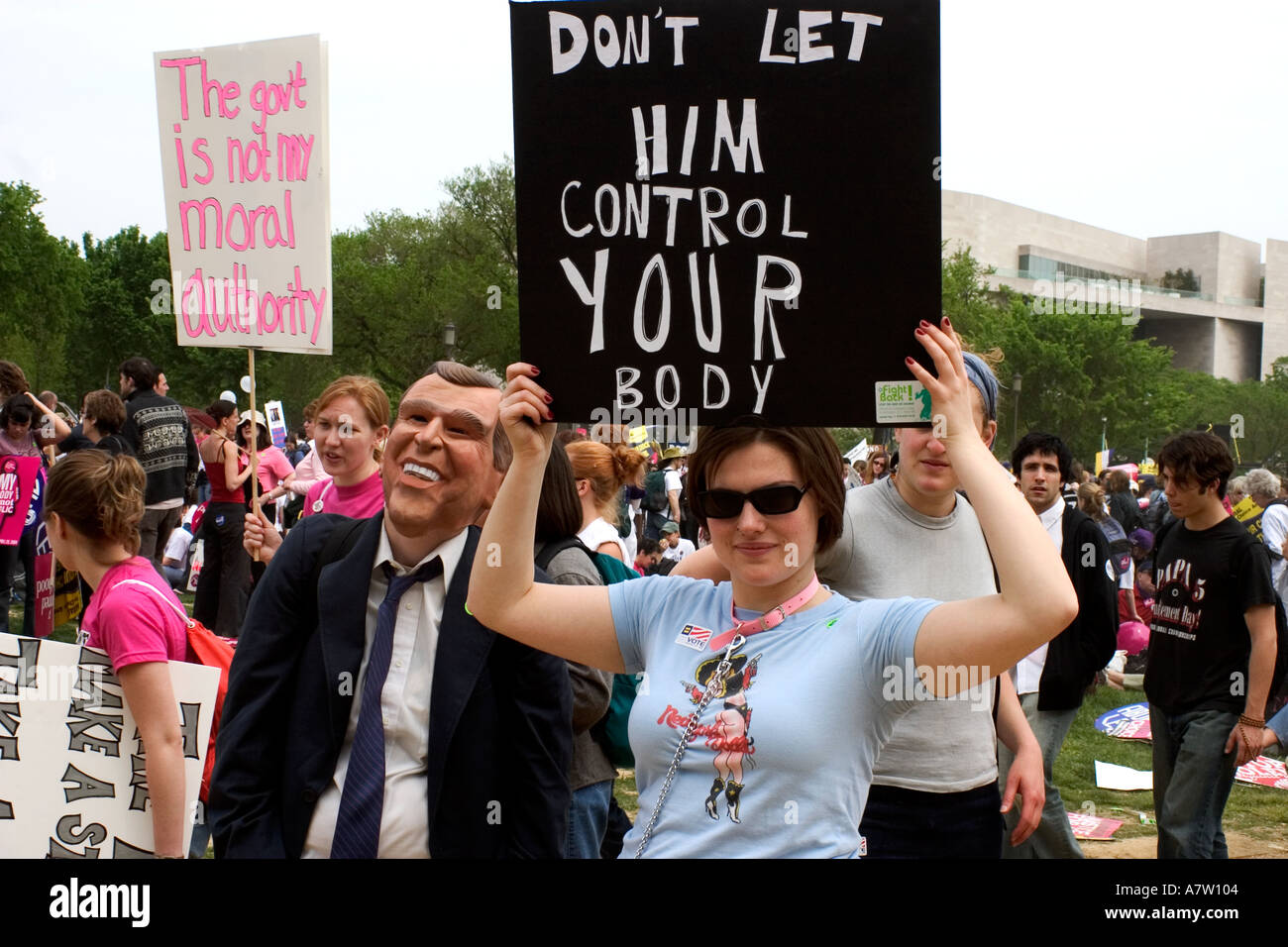 A woman holds sign as she stands next to somebody wearing George W Bush mask This was at the Pro Choice Rally on April 25 2003 Stock Photo