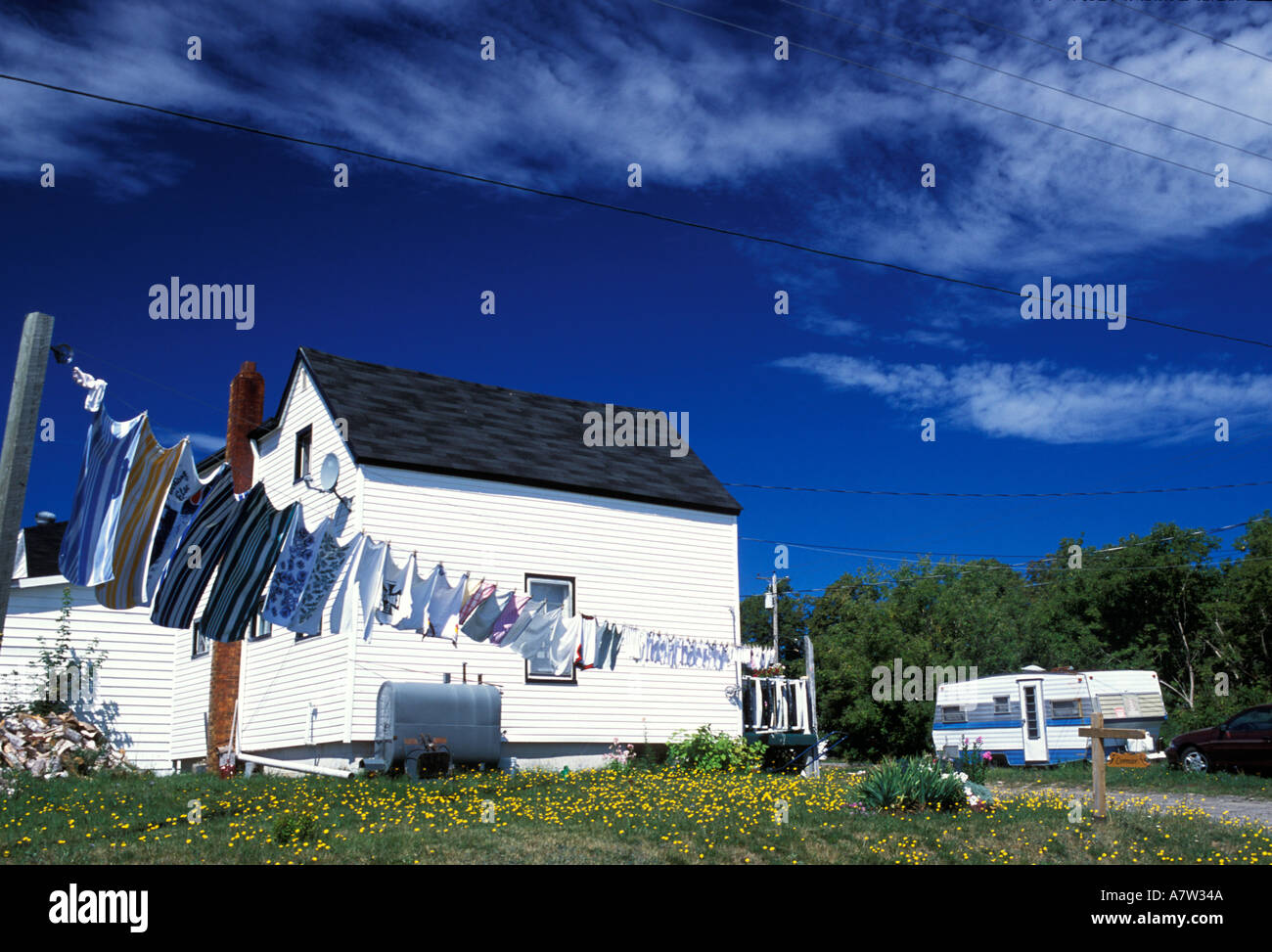Laundry swinging in the breeze in front of a white clapboard house with trailer caravan in Bouctouche New Brunswick Canada Stock Photo