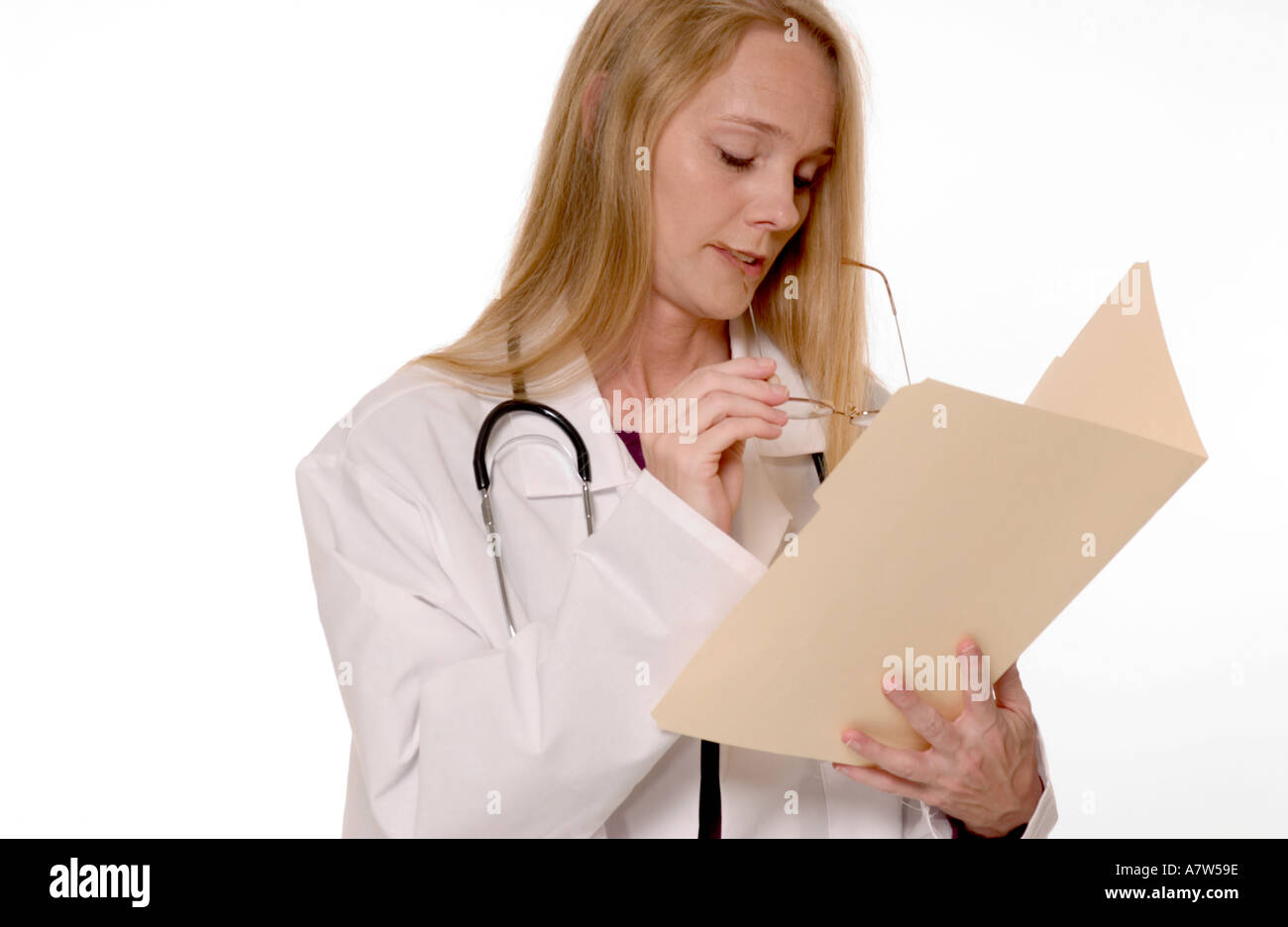 Caucasian female general practitioner looking down while writing notes in patient’s folder at medical office, USA. Stock Photo