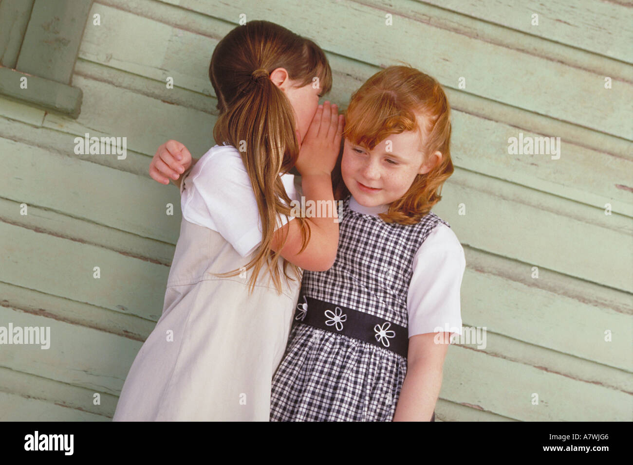 two girls standing on a porch whispering to each other Stock Photo - Alamy