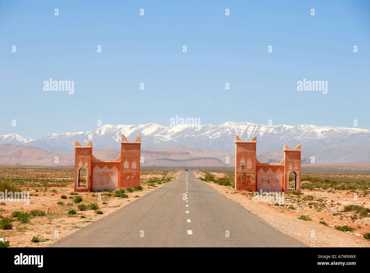 Straight street runs through a gate towards snowcapped mountains of the High Atlas between Tinerhir and Boumalne-du-Dades Moroc Stock Photo