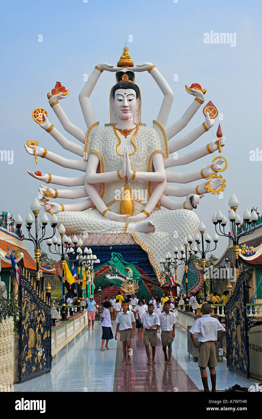 Visitors at the enormous multi armed carved statue of a buddhist deity at Wat Nuan Naram Stock Photo