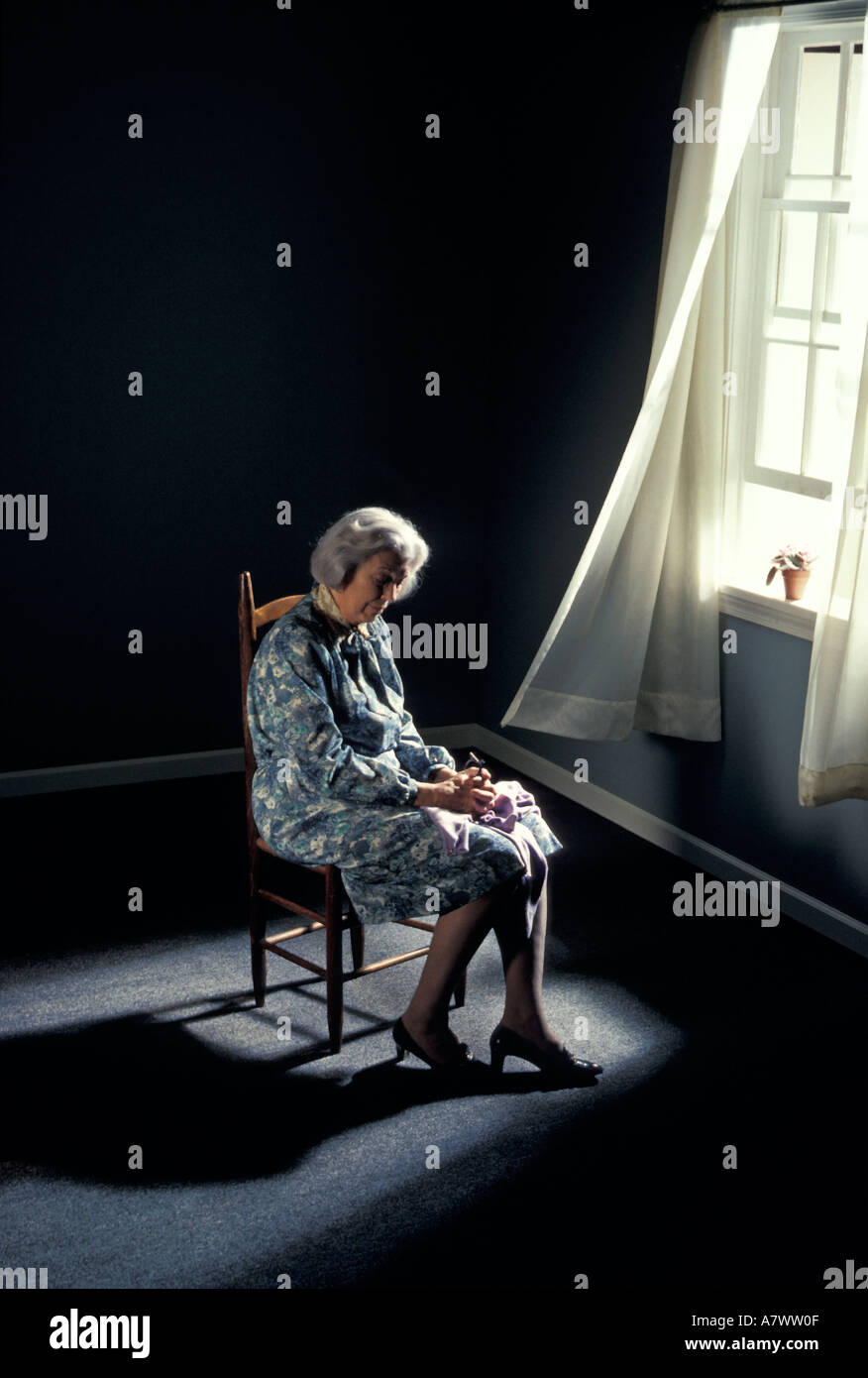 depressed lonely elderly woman by window squander waste dissipate ravage misuse desecrate devastate widow retirement abuse Stock Photo