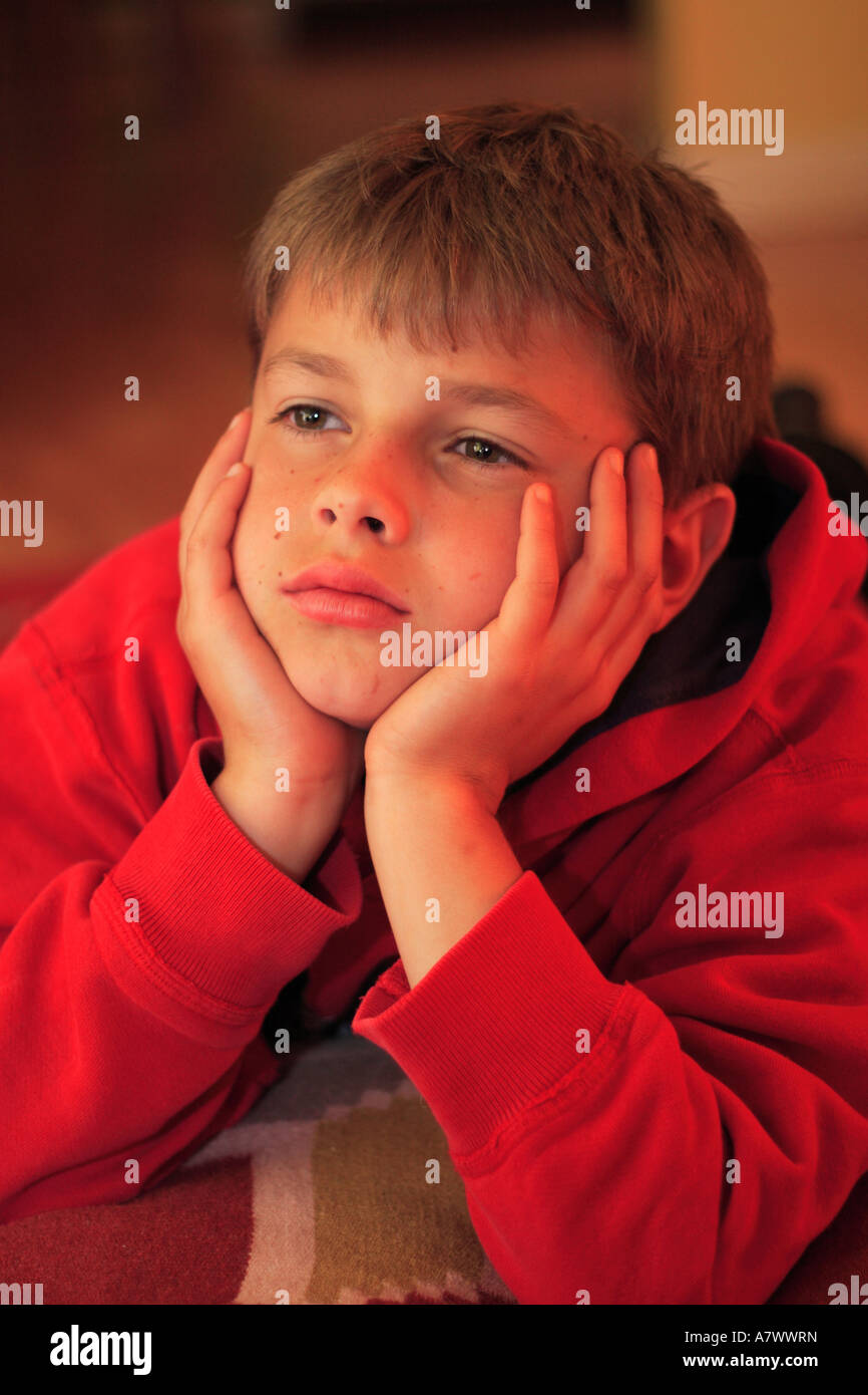 Young boy watching television in the evening while lying on lounge floor Stock Photo