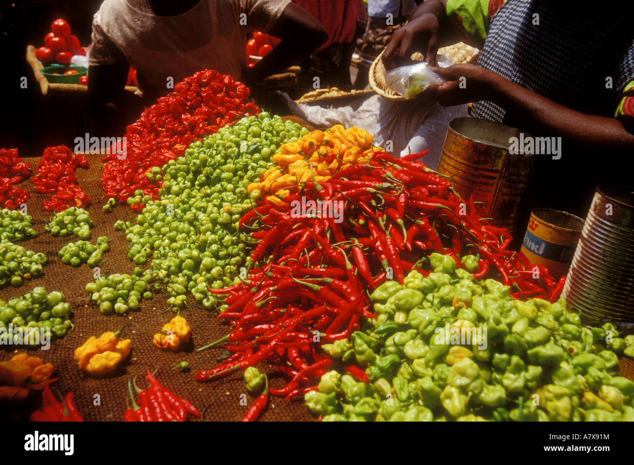 Ghana, Accra, Makola market, assorted colorful peppers for sale and customer holding out money
