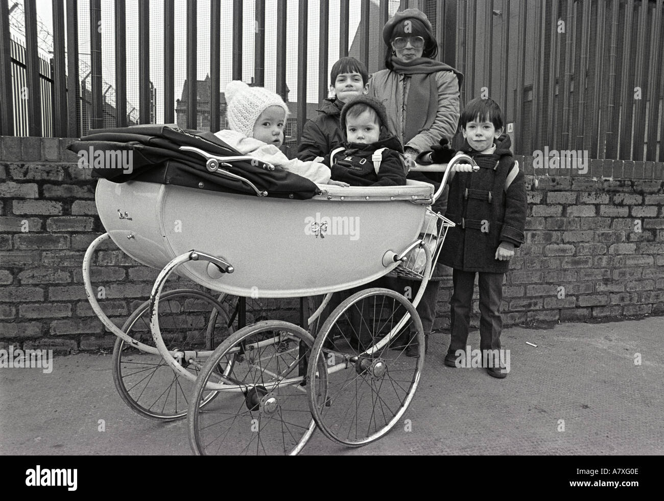 Black and white photograph of a woman and family with baby in old style pram in Glasgow Stock Photo