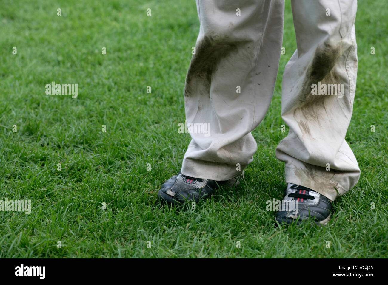 Young boy standing on grass with dirty trousers and trainers Stock ...