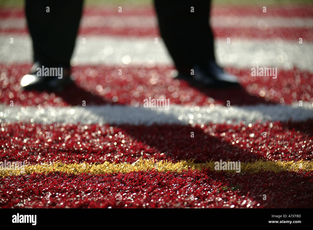 BUSINESSMANS FEET ON MULTI-COLOURED SPORTS ARENA TURF Stock Photo