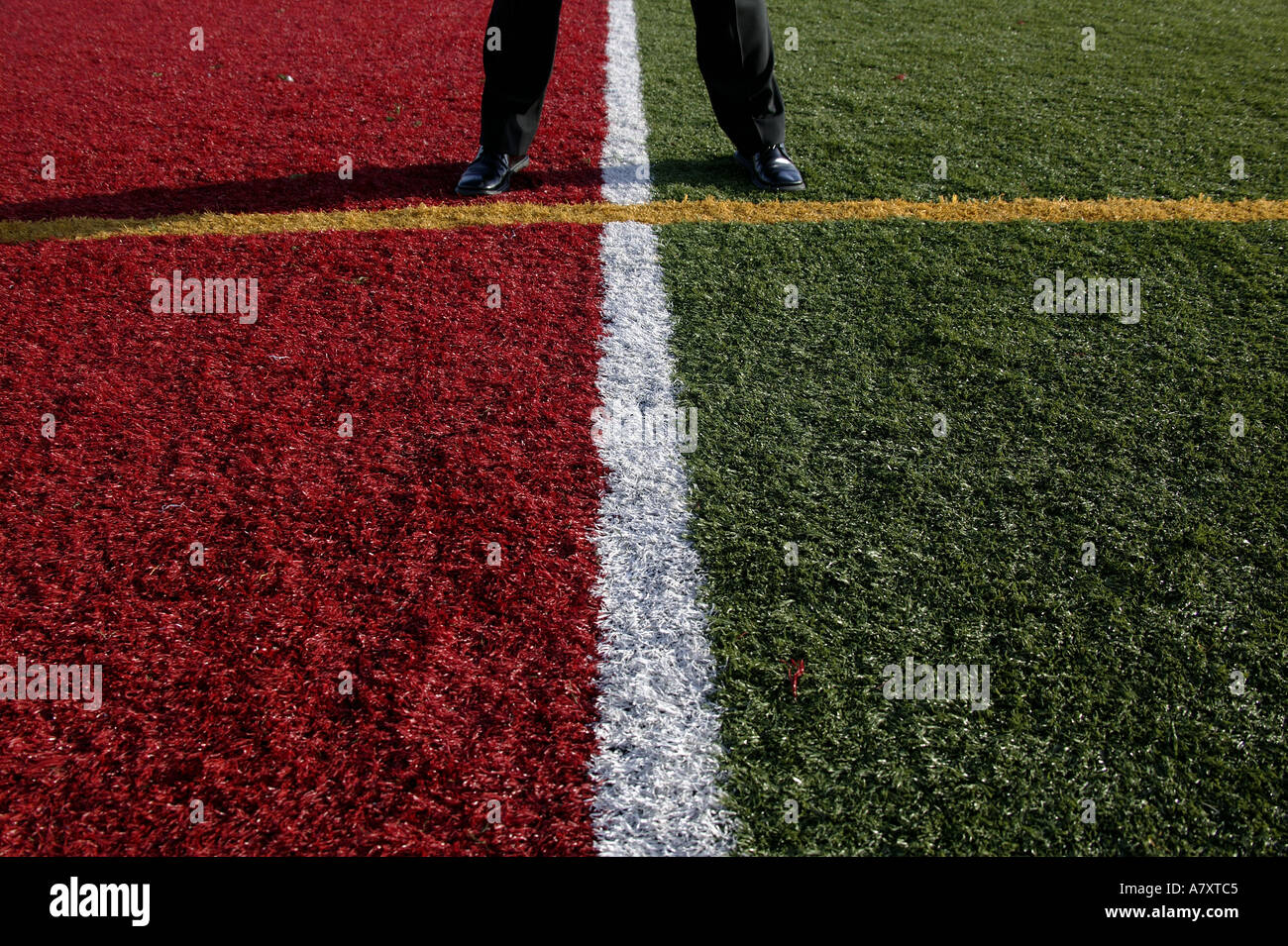 BUSINESSMANS FEET ON MULTI-COLOURED SPORTS ARENA TURF Stock Photo
