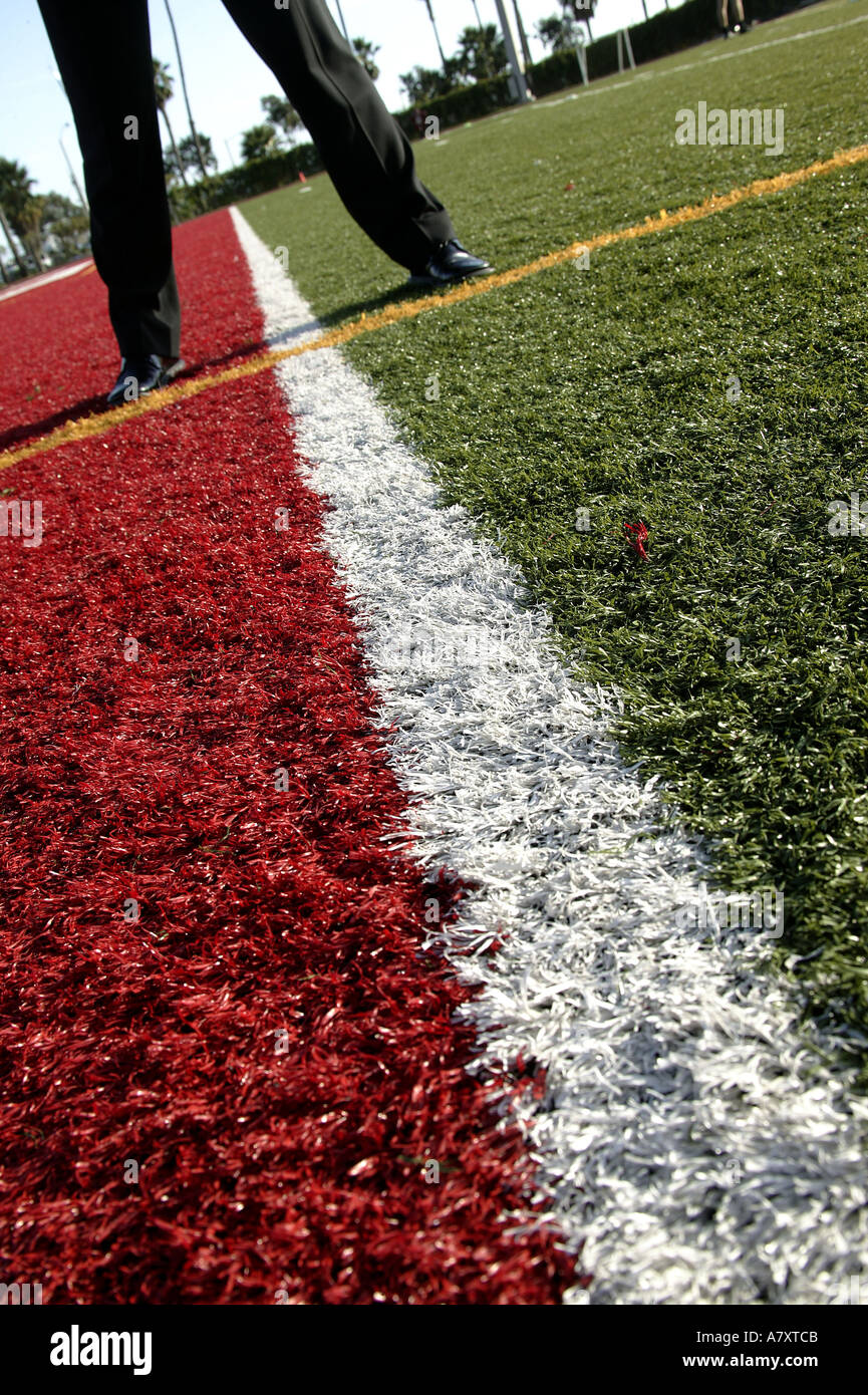 BUSINESSMANS FEET ON MULTI-COLOURED SPORTS ARENA TURF Stock Photo