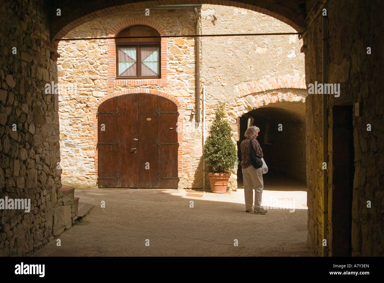 A woman walks through a stone arch in the picturesque roads of ...