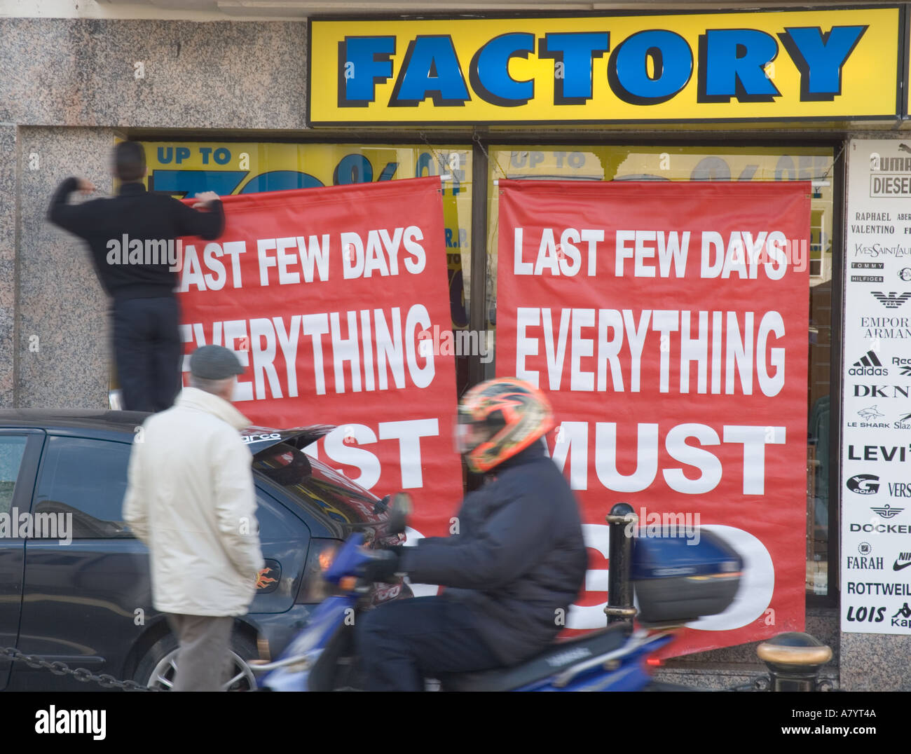Man putting up sign for shop sale which says Last Few Days Everything Must Go Stock Photo