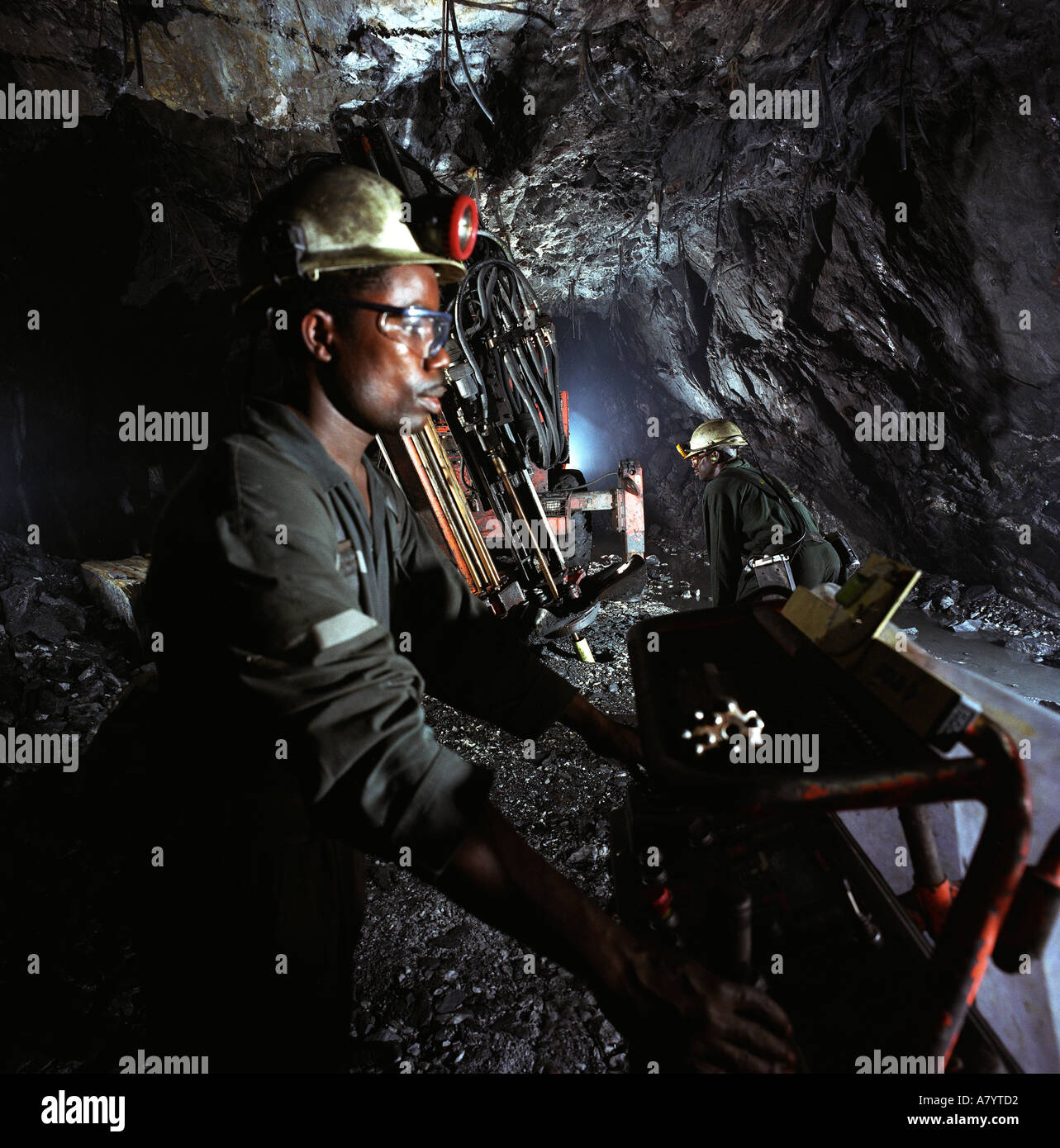 Mining operations for transporting, managing & the processing of gold ore. Miners drilling for rock core samples at underground gold mine in Ghana Stock Photo