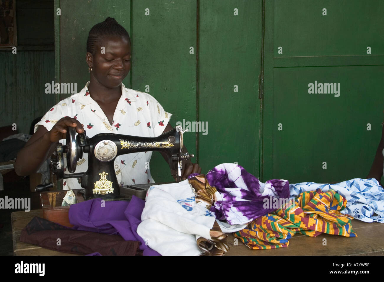 Ghanaian woman seamstress using hand operated sewing machine making and