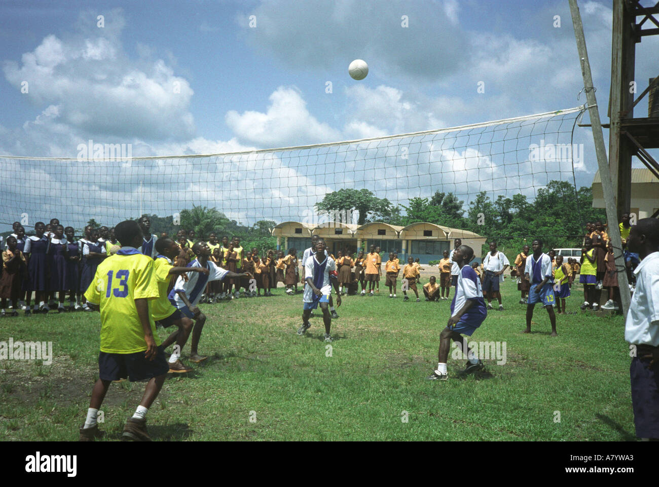 Teenage boy students playing in a school volleyball match on sports ground with supporters watching from side lines, Western Region, Ghana West Africa Stock Photo