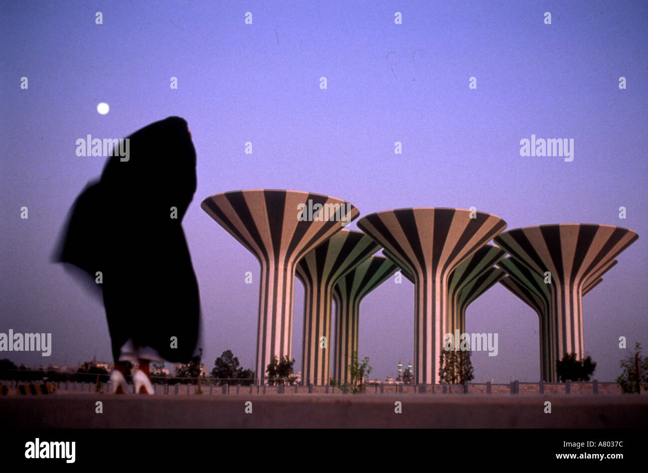 Arab Woman In Black Burka Blowing In Wind Reveals White Shoes Near Kuwait City Water Towers At Dusk As Moon Rises Stock Photo Alamy