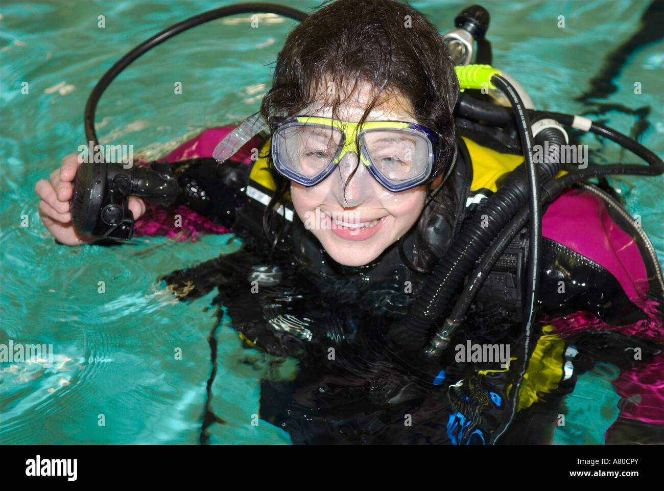 Woman scuba diver with colourful drysuit looking up and smiling from