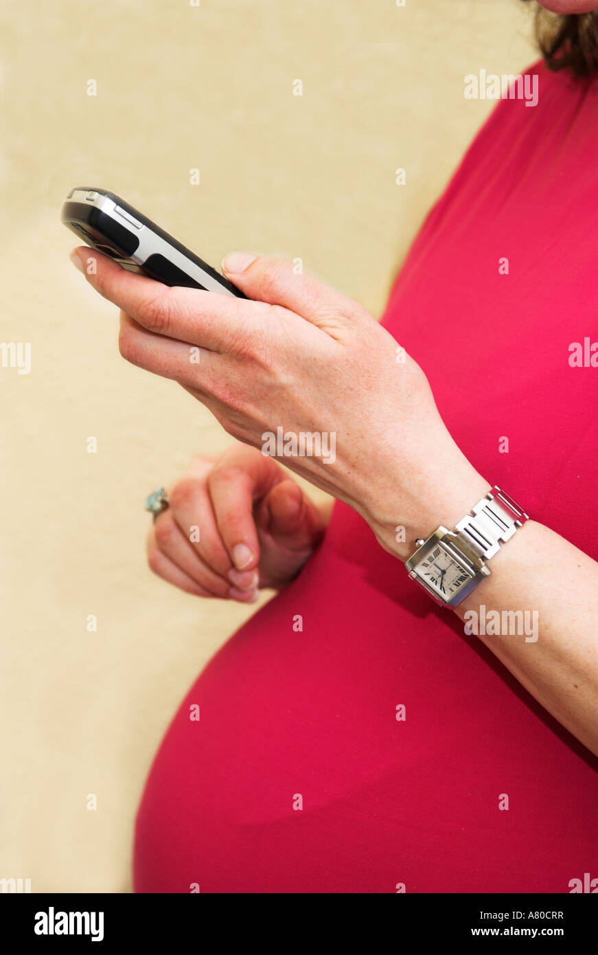 Closeup of nine months pregnant woman holding and using a mobile phone Stock Photo