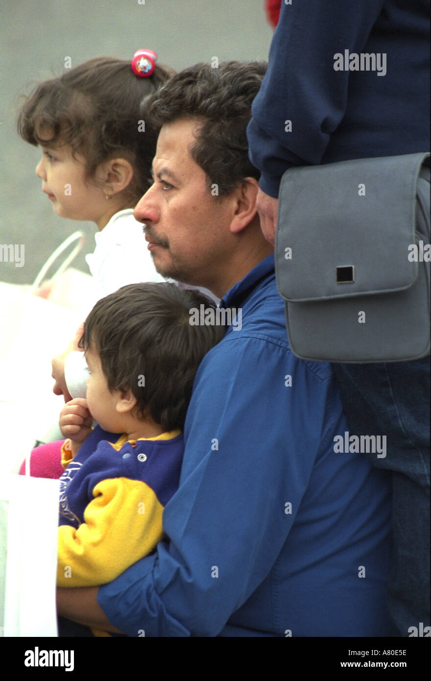Hispanic dad age 32 sitting with kids age 4 and 1 at Cinco de Mayo. St Paul Minnesota USA Stock Photo