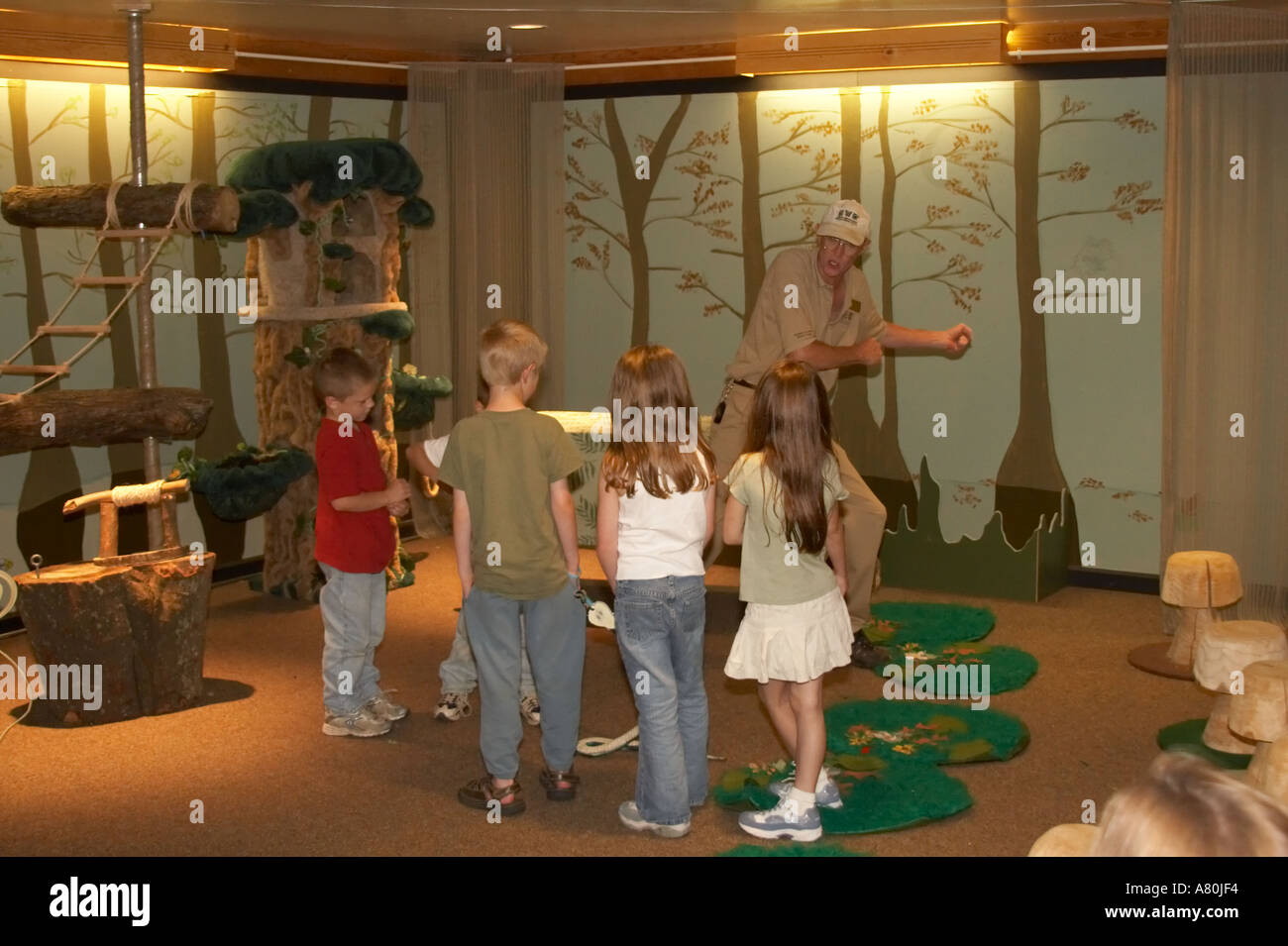 Children practicing snake handling techniques in a nature classroom