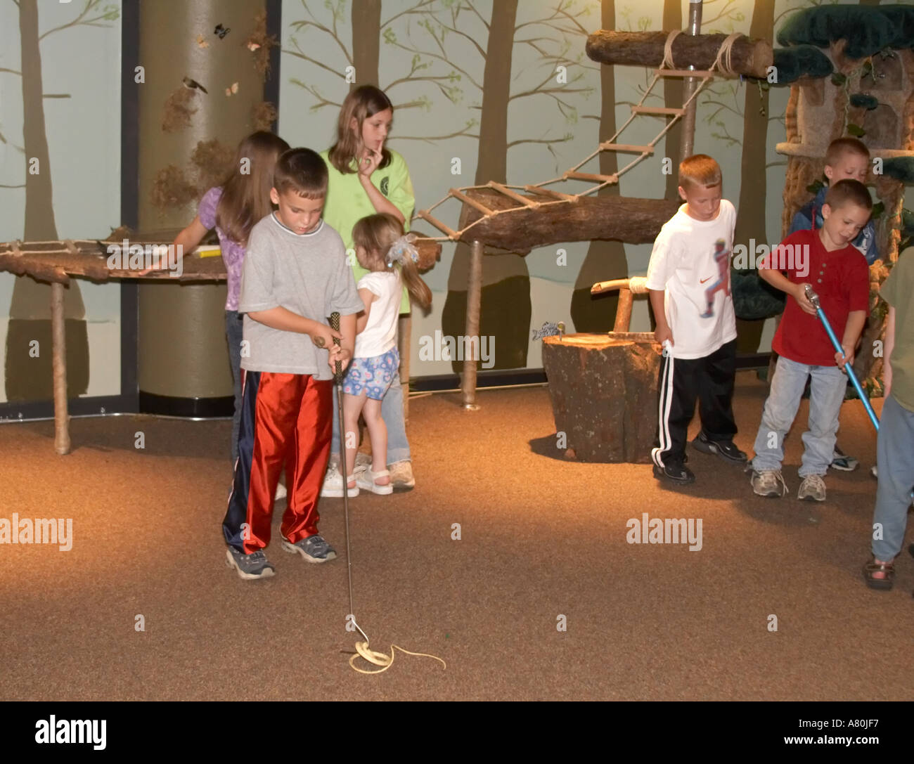 Children practicing snake handling techniques in a nature classroom