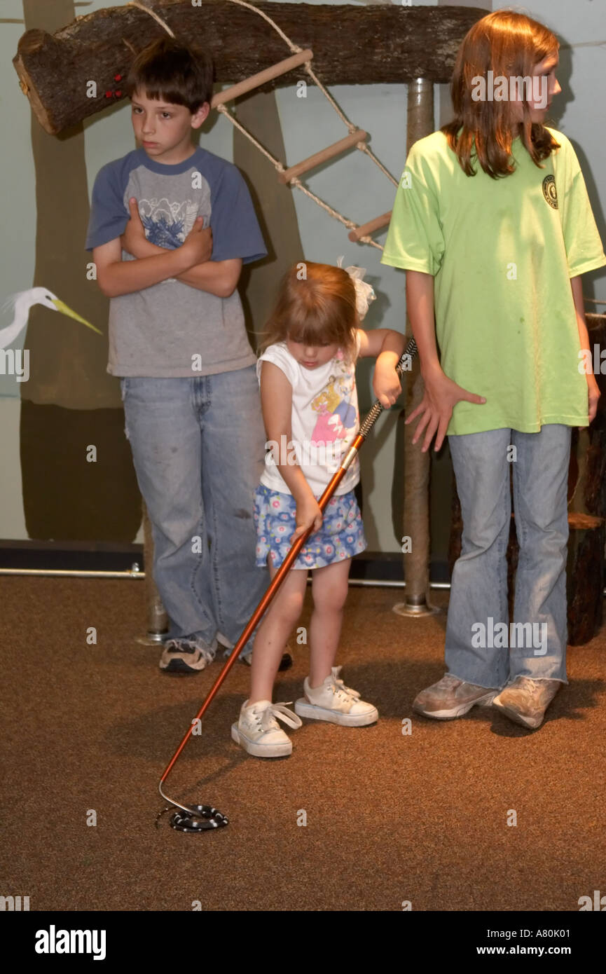 Children practicing snake handling techniques in a nature classroom