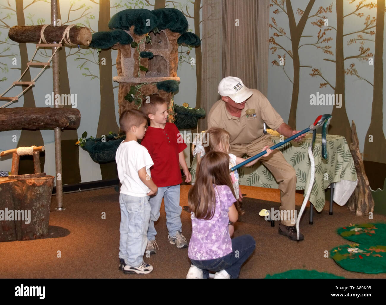 Children practicing snake handling techniques in a nature classroom