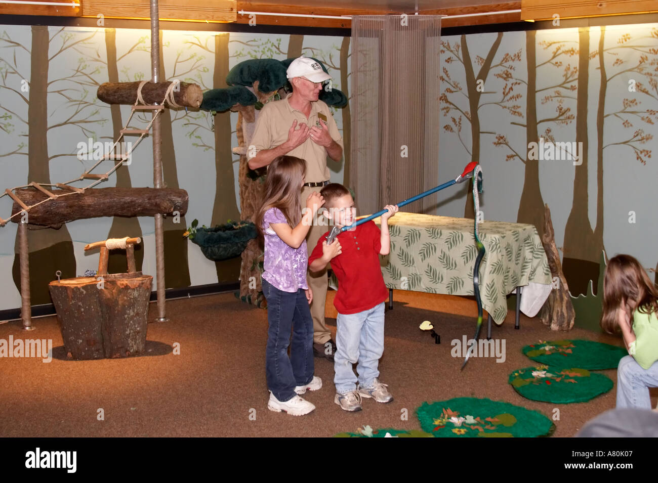 Children practicing snake handling techniques in a nature classroom