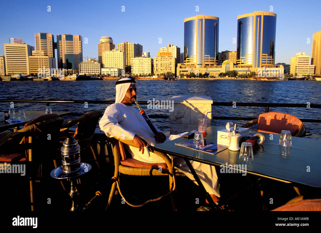 United Arab Emirates, Dubai, Dubai town, Dubai Creek, Emirati smoking narguile in front of the towers of the business District Stock Photo