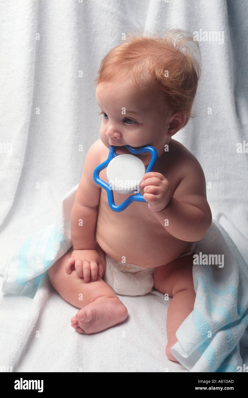 baby chews on toy wrapped in blanket and diaper Stock Photo Alamy
