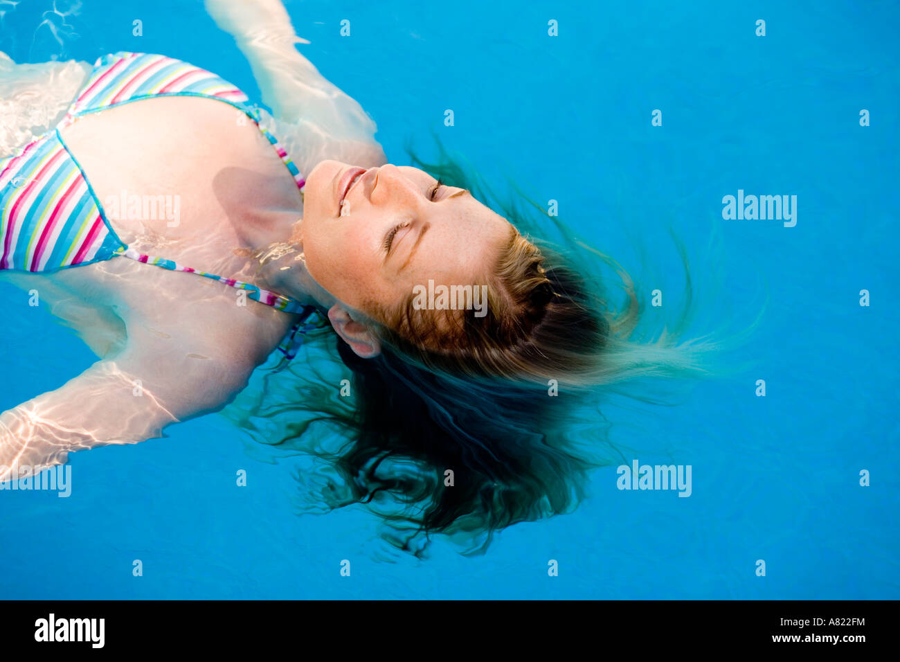 A young woman floating in a swimming pool Stock Photo - Alamy