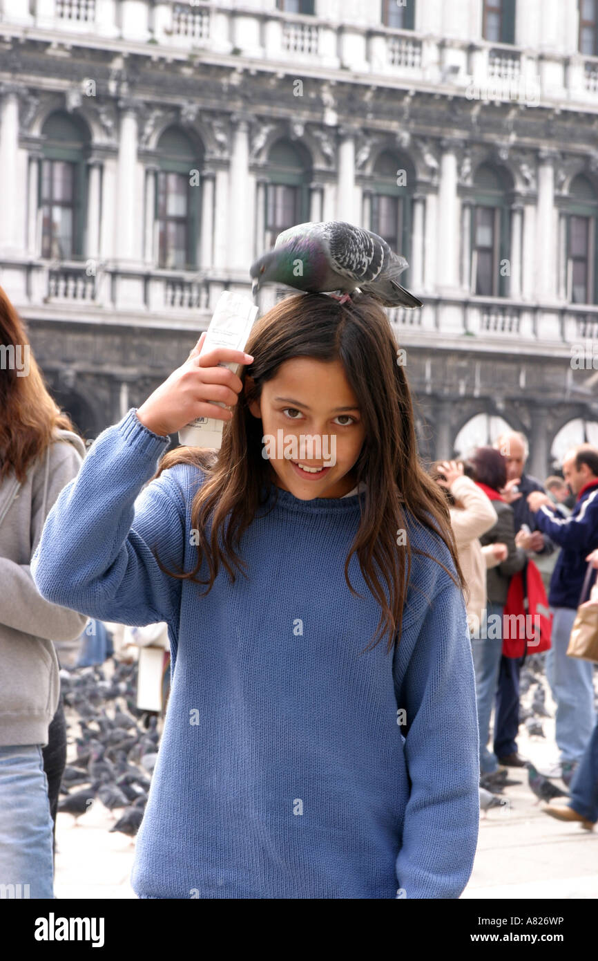 A young girl with a pigeon on her head, St Marks Square, Venice, Italy Stock Photo