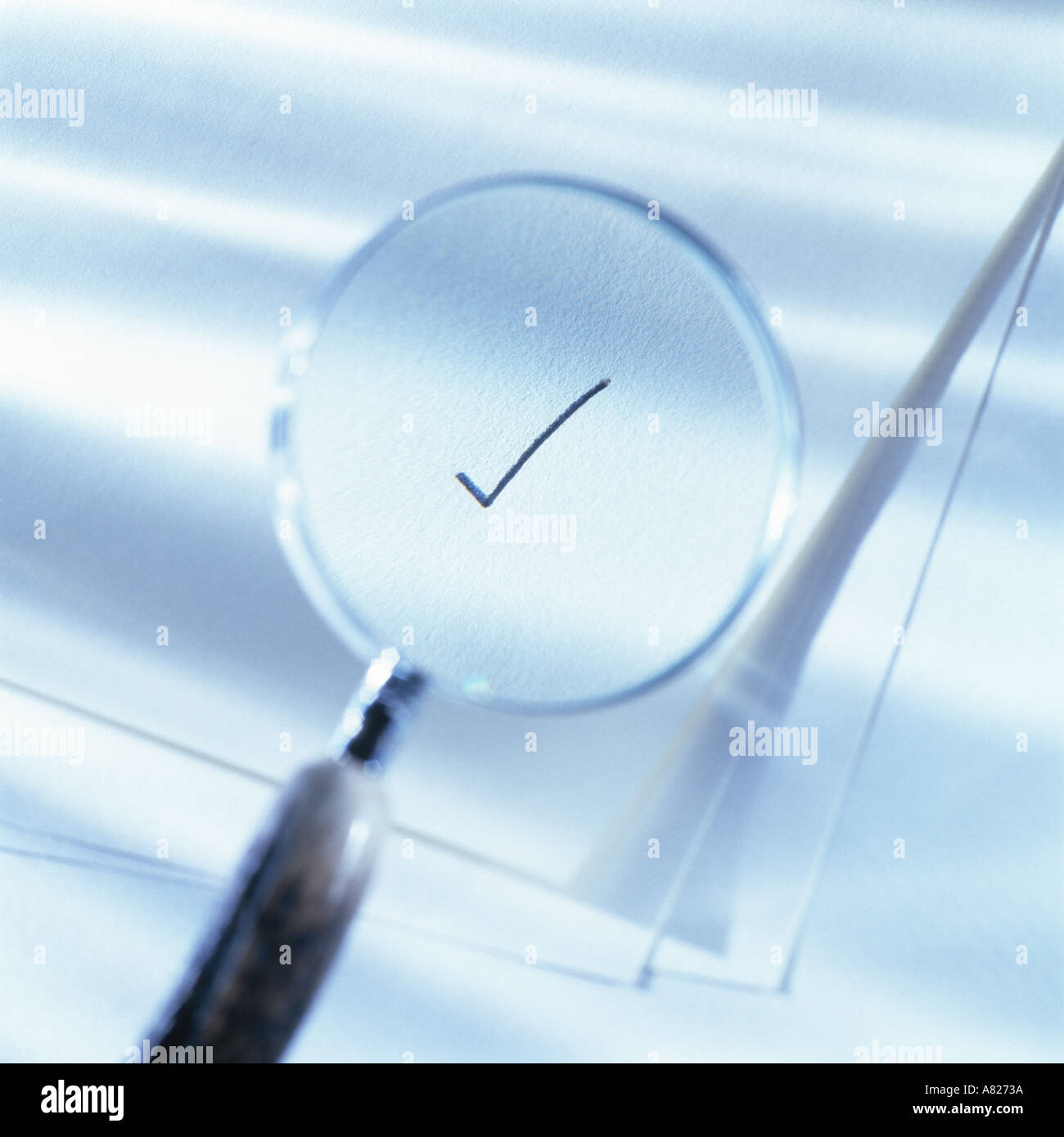 Magnifying glass over blank papers highlighting a check mark blue tone Stock Photo