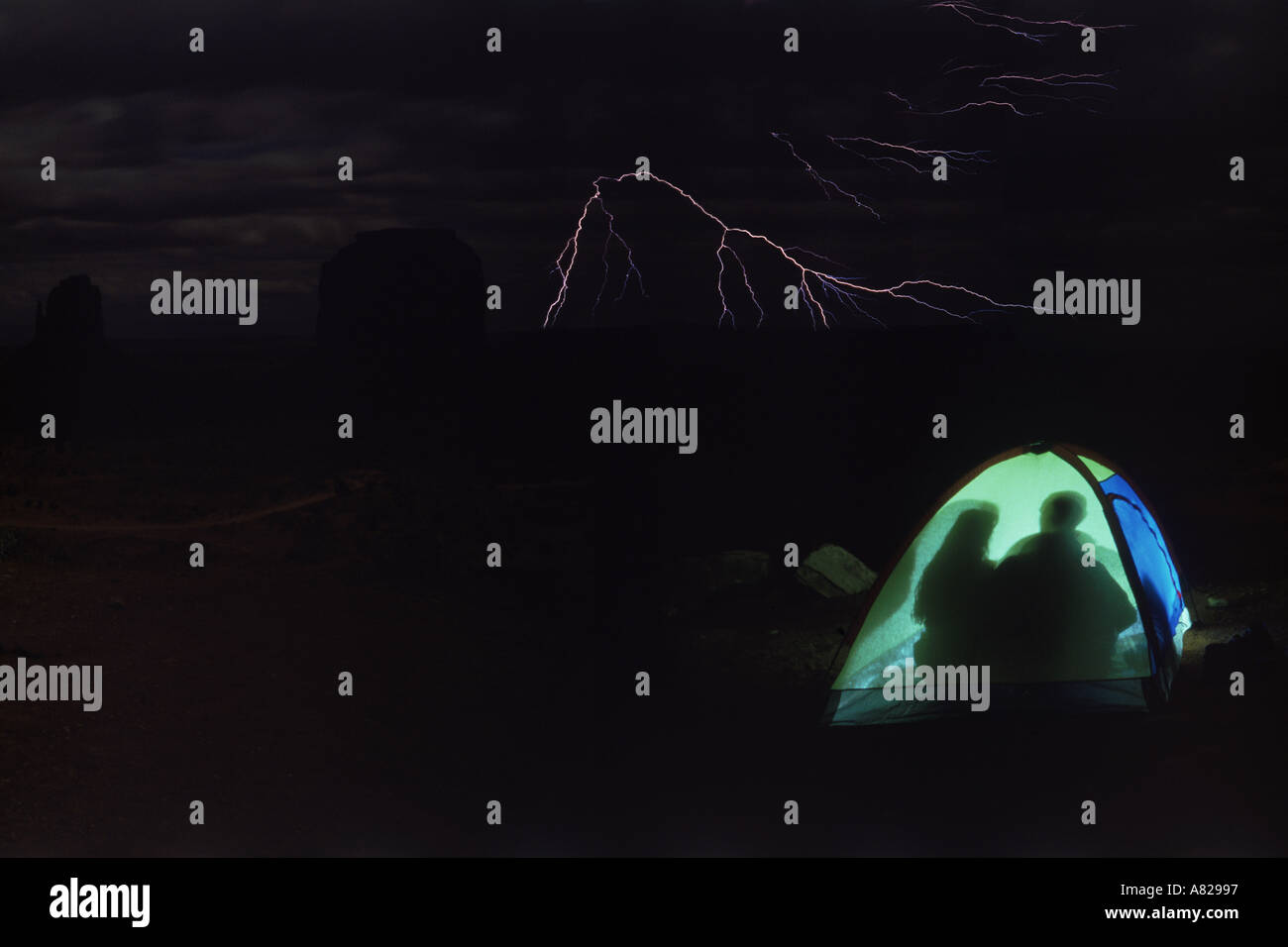 Couple camping in tent in Monument Valley during lightning storm Stock