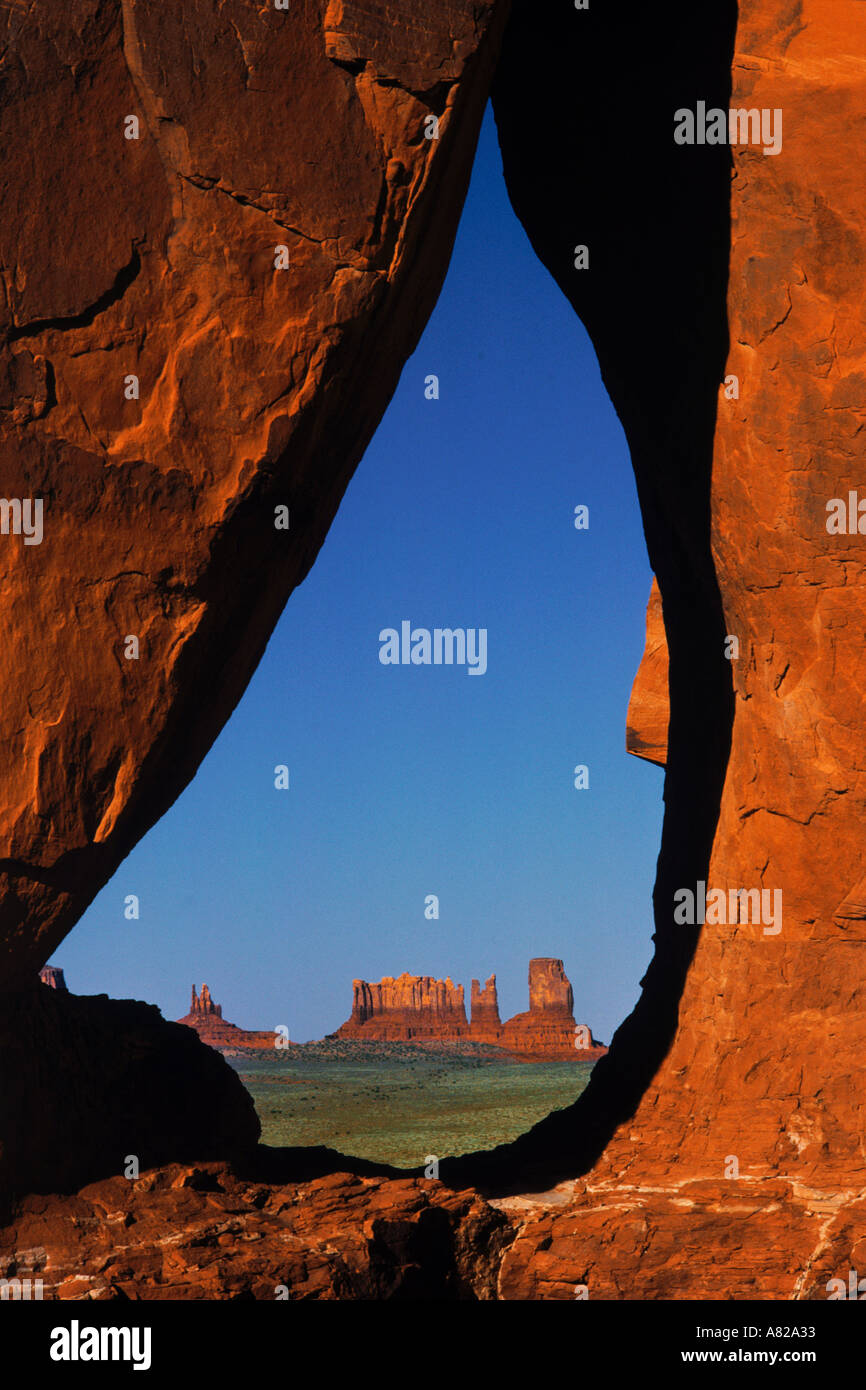 View of  distant Monument Valley framed by hole in desert rock wall Stock Photo