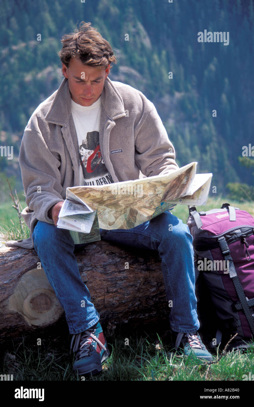Walker sitting on a log reading map Stock Photo