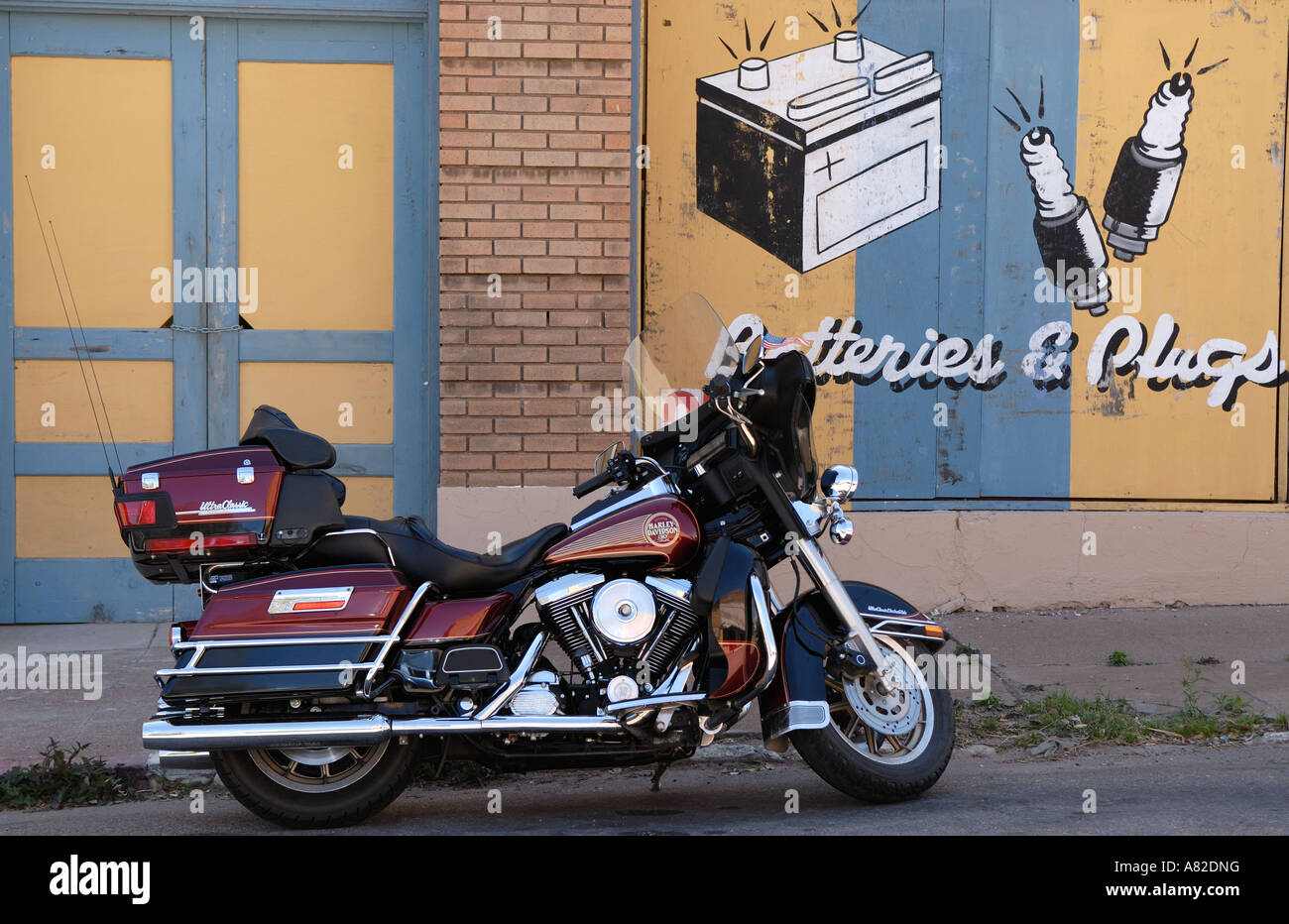 Harley Davidson on sidewalk in front of abandoned car shop in a modern ghost town. Stock Photo