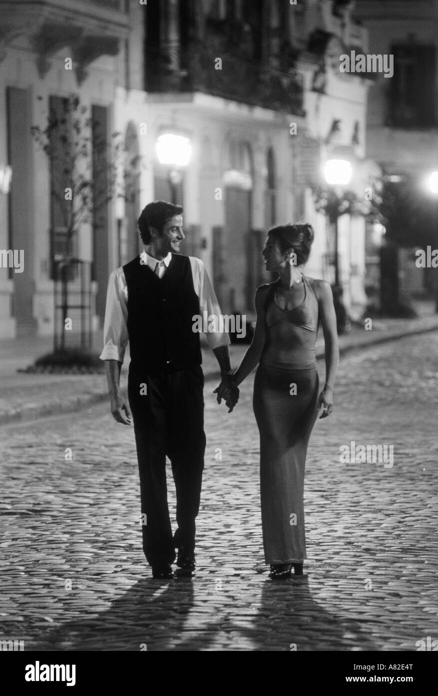 Argentine couple holding hands walking on cobblestone streets of San Telmo at night in Buenos Aires Stock Photo