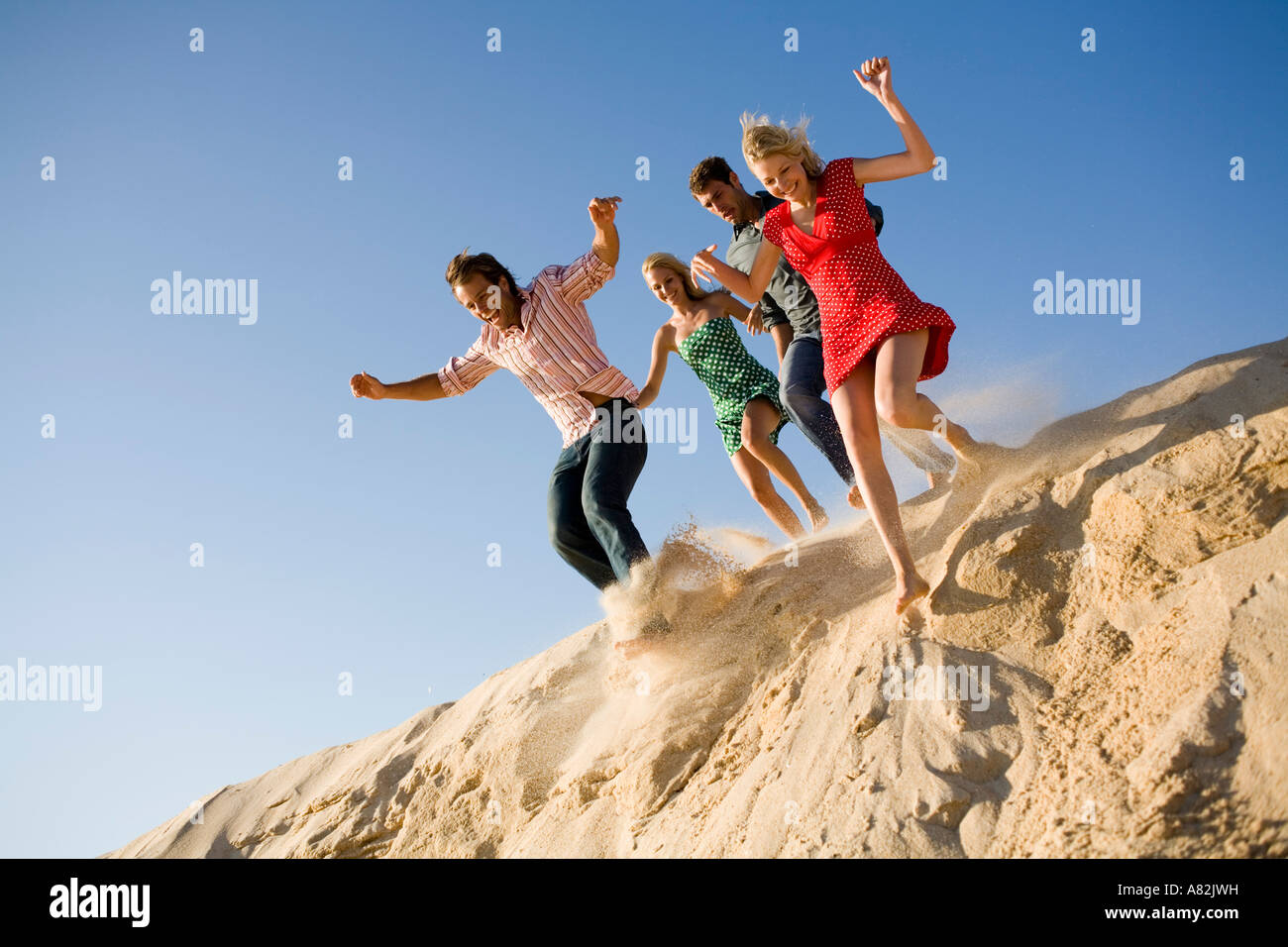 Two couples at the beach jumping off a sand dune Stock Photo Alamy