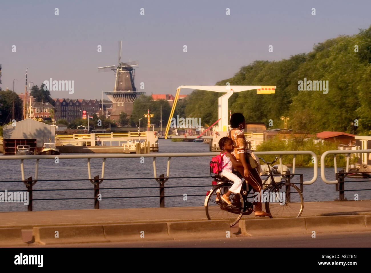 Amsterdam black woman and child on a bicycle backgound draw bridge and windmill Stock Photo