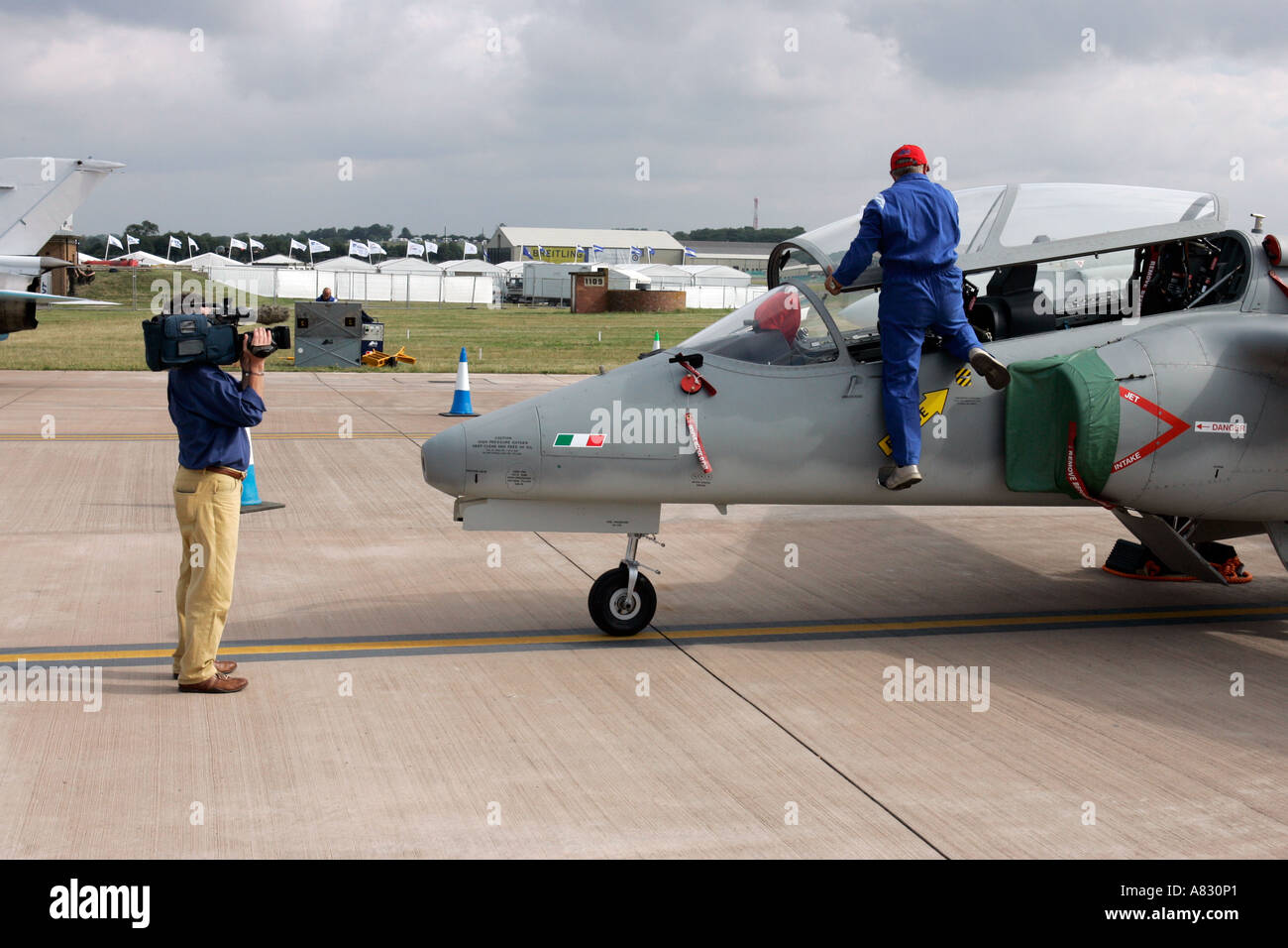 Cameraman films technician as he attends to an Italian jet fighter at airshow, both unidentifiable Stock Photo
