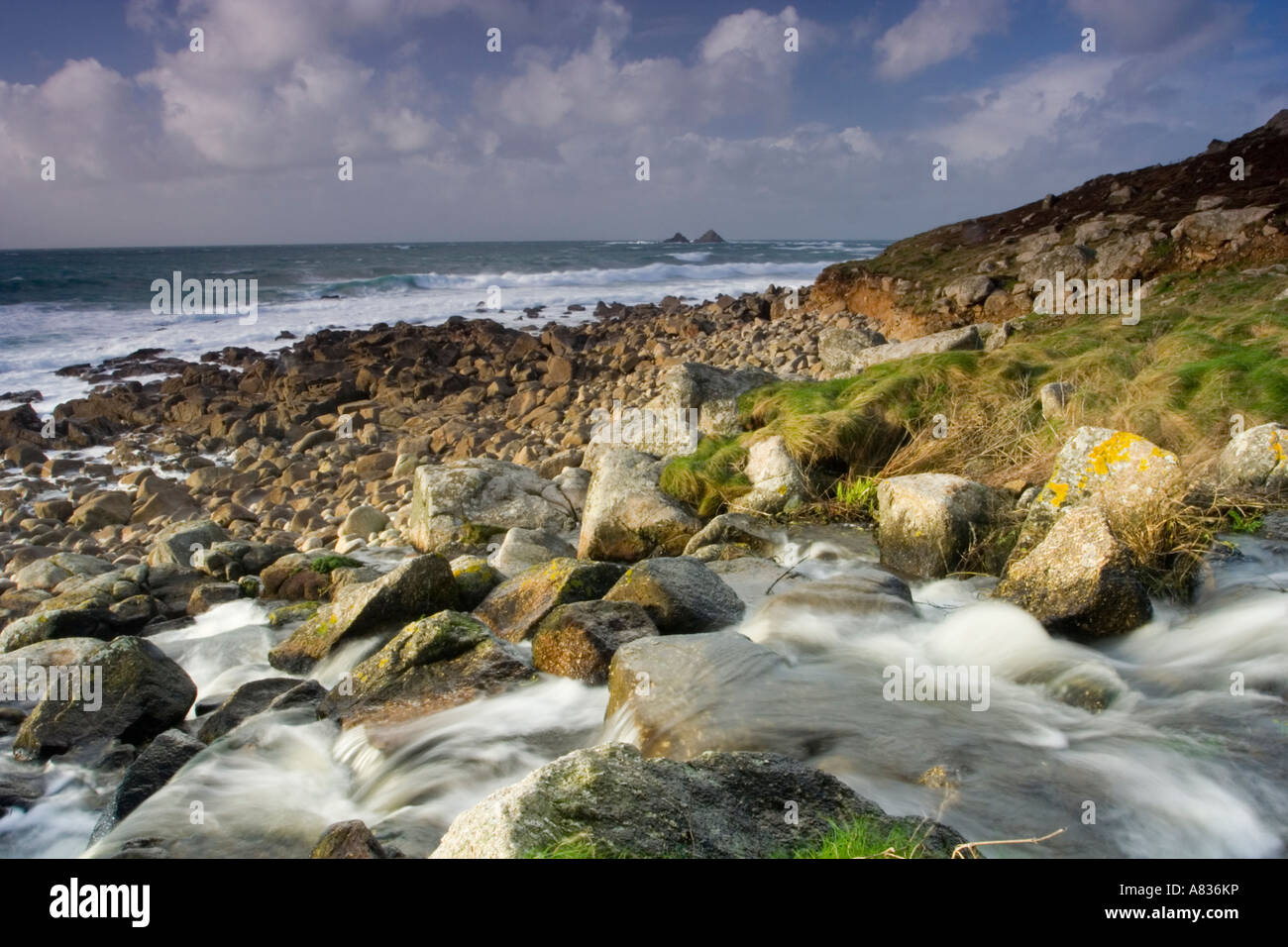 Flowing river meeting a boulder beach at Nanjulian Cornwall UK Stock Photo