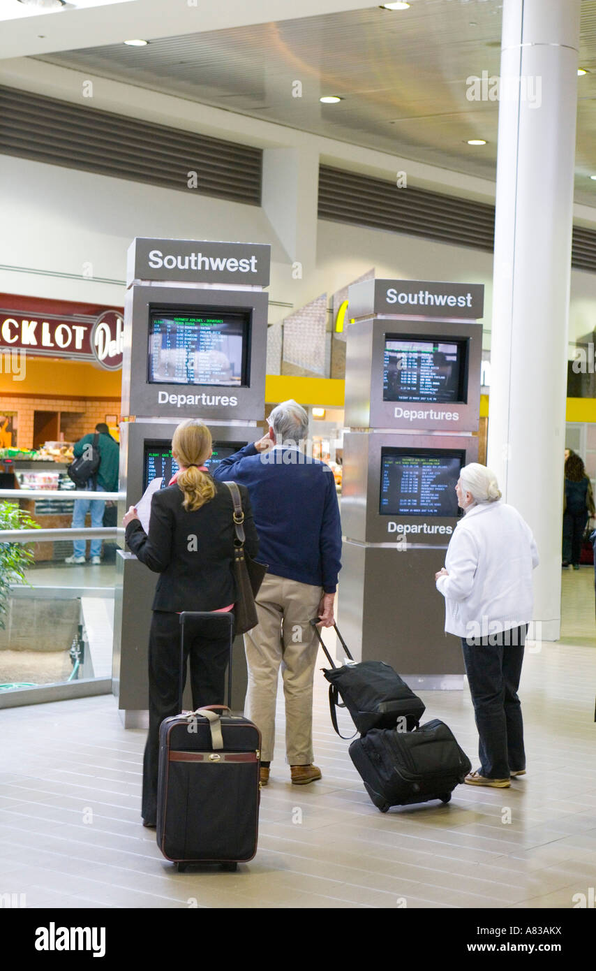 Travelers check their departure times in the Southwest terminal at Los Angeles International Airport Stock Photo