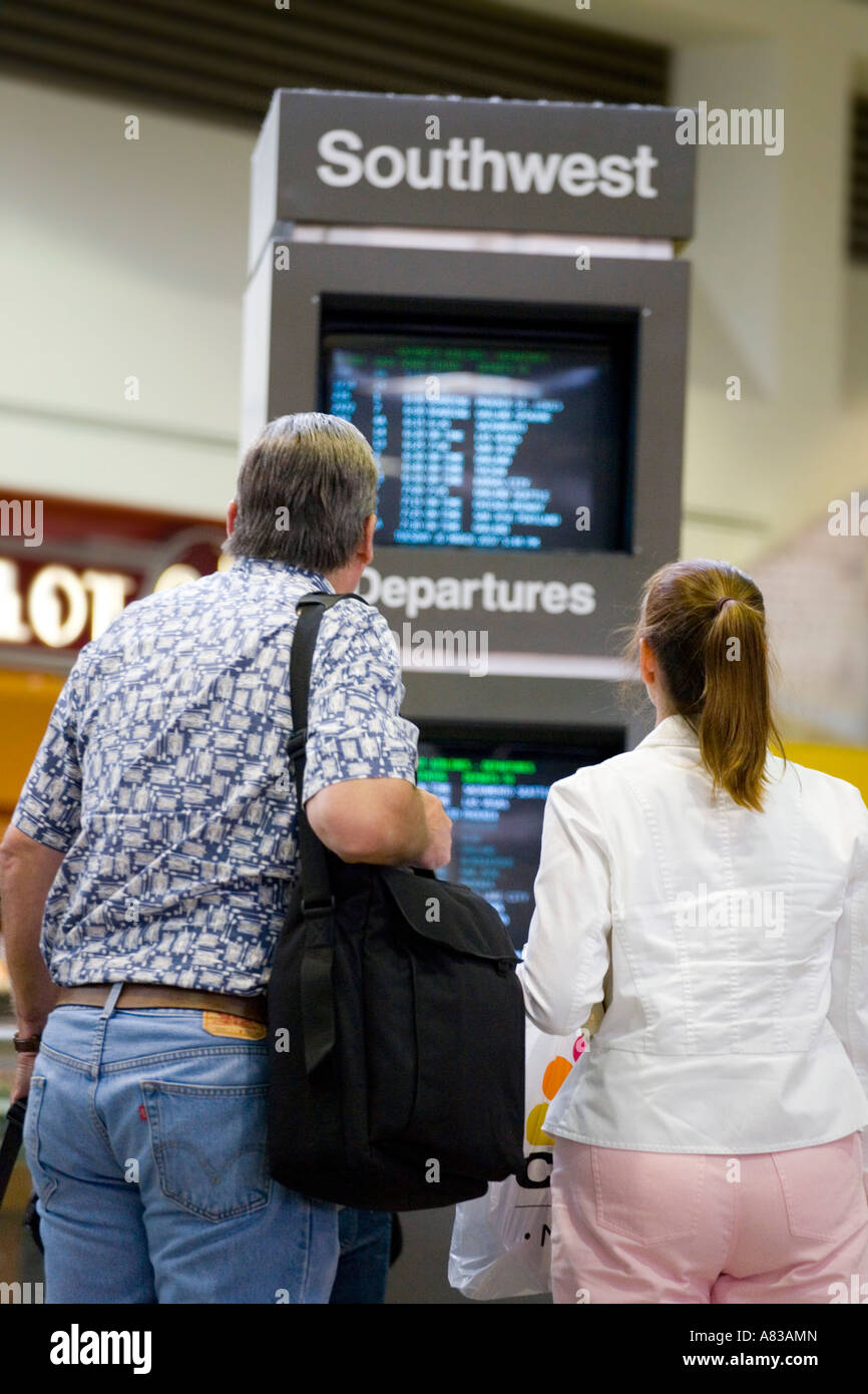 Travelers check their departure times in the Southwest terminal at Los Angeles International Airport Stock Photo