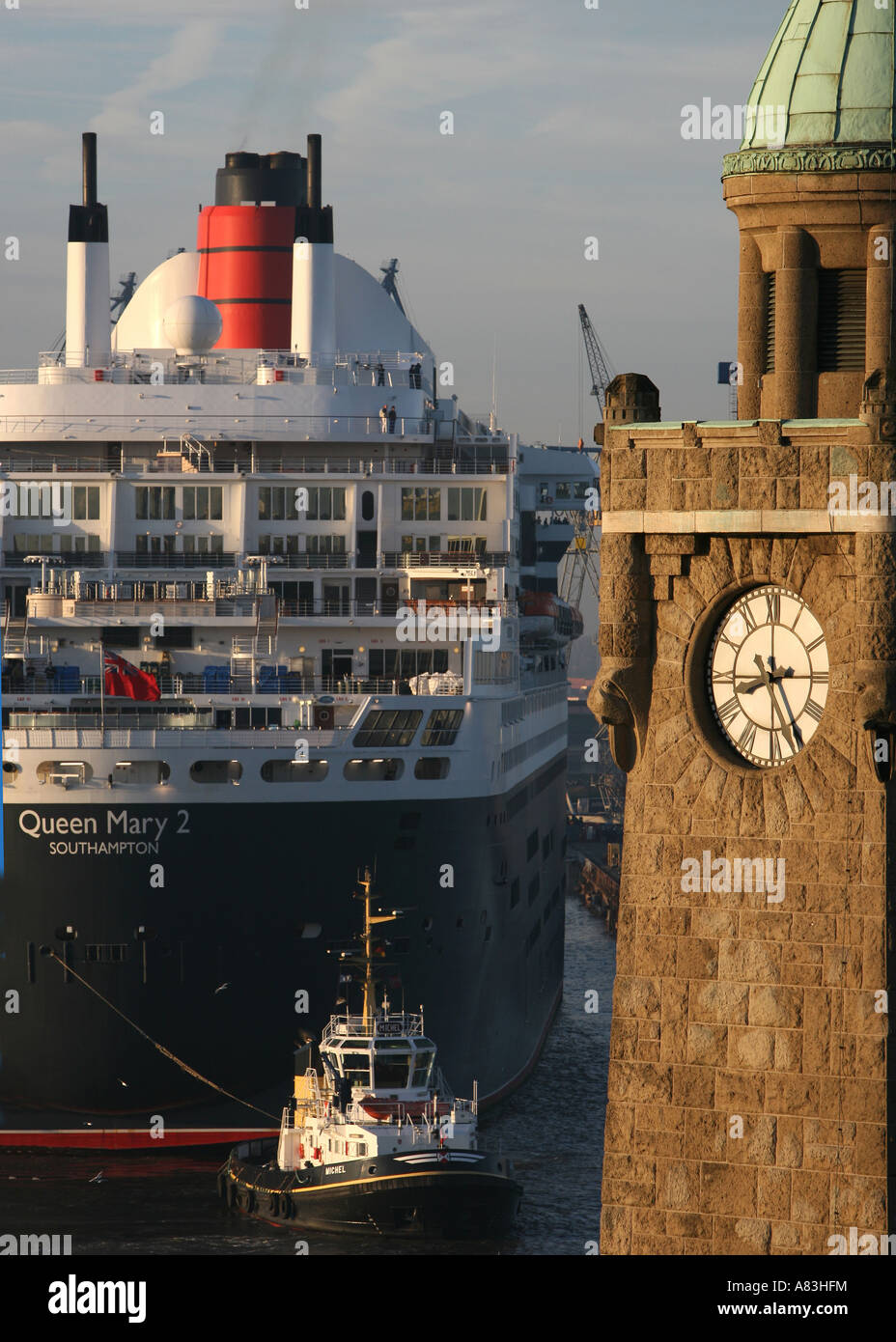 Queen Mary II approaching dry dock of Blohm+Voss in Hamburg, Germany, historic clock tower at St. Pauli Landungsbruecken Stock Photo