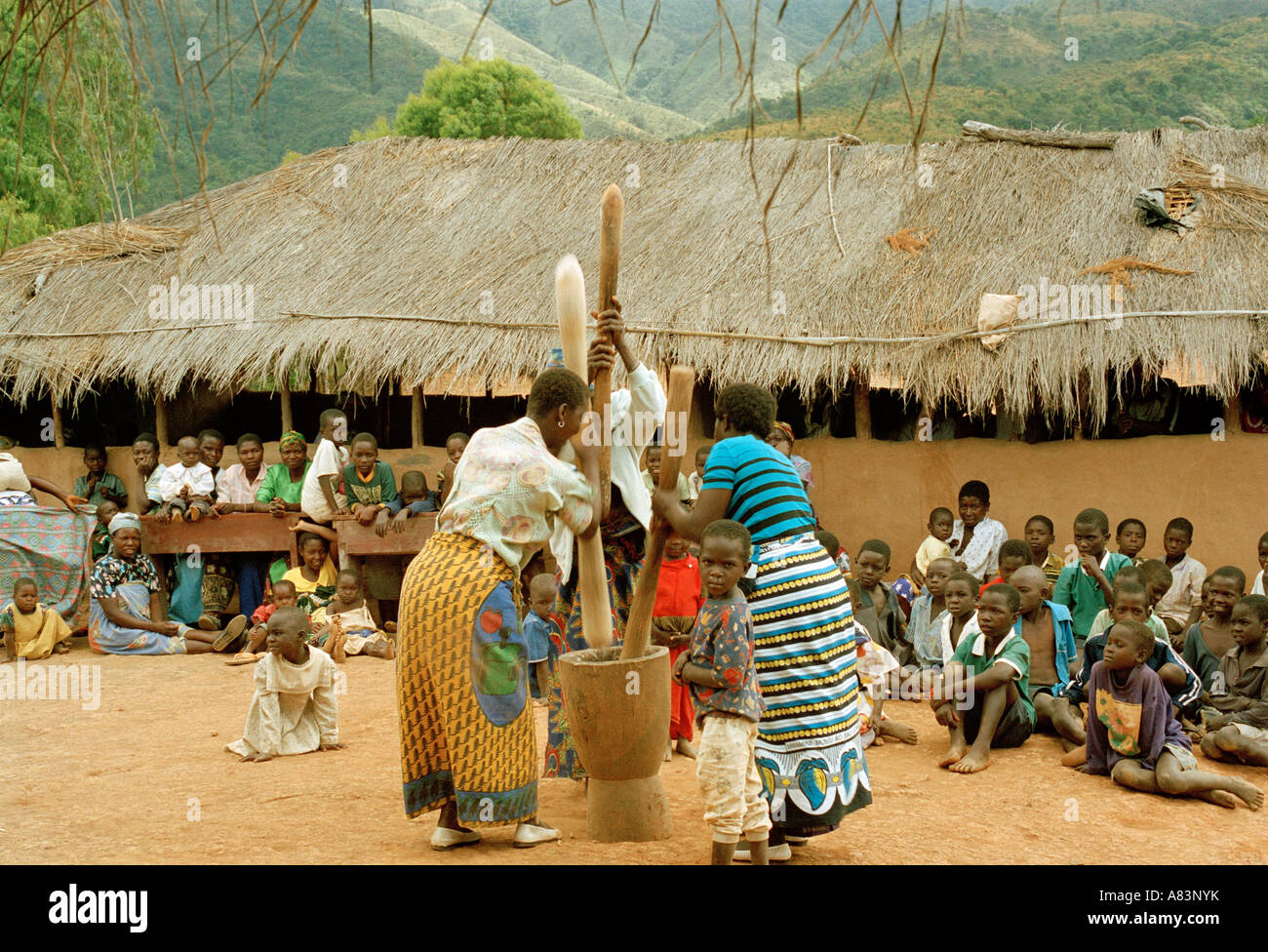 Local women grinding maize, in front children, Malawi, East Africa