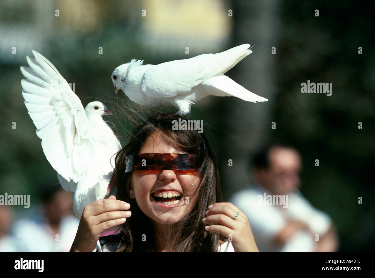 Spain. Andalusia. Seville. Young girl enjoying scary fun with the famous white pigeons of Seville. Stock Photo